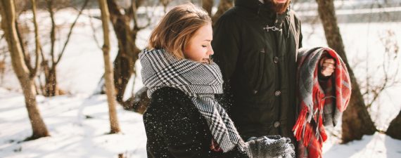 Young hipster couple having a walk in winter park near the frozen lake
