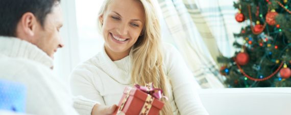 Young man giving his girlfriend Christmas present