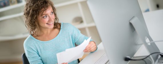 Young woman paying bills online using her desktop - home finances concepts