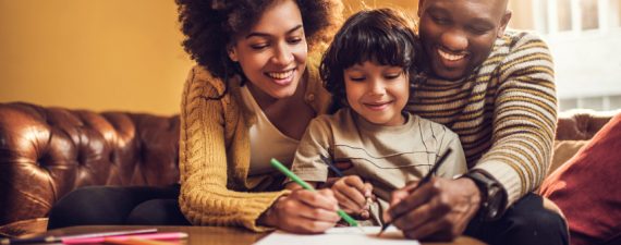 Young African American family having fun while drawing together at home.