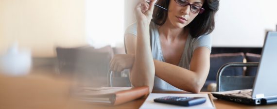 Woman sitting at desk looking at notebook