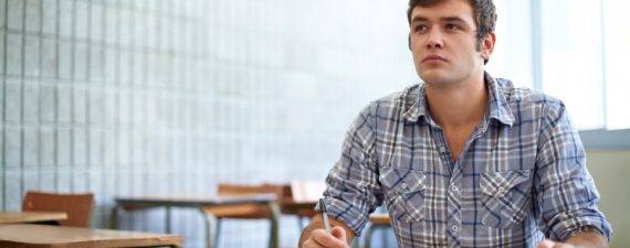Shot of student sitting in a classroom going over his work