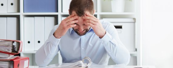 Young business man under stress with headache and migraine