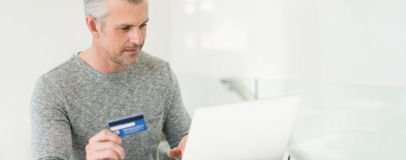 Adult man shopping online at home using a laptop computer