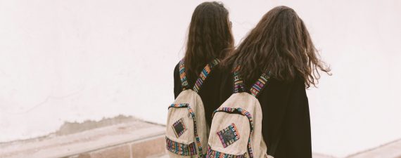 students twins with backpacks walking