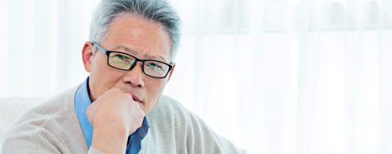 Asian senior man sitting at home and contemplating