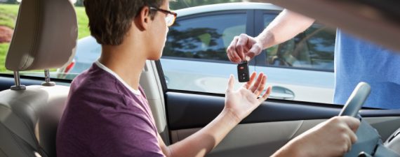 Cropped view of teenage driver taking car keys from father. Focus on key.