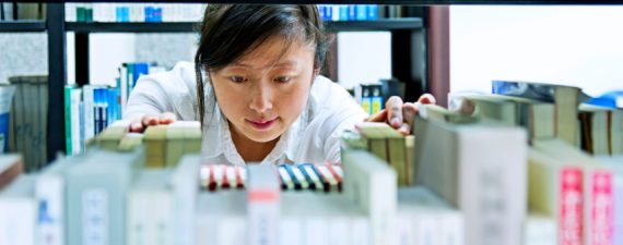 Asian young woman choosing book in library